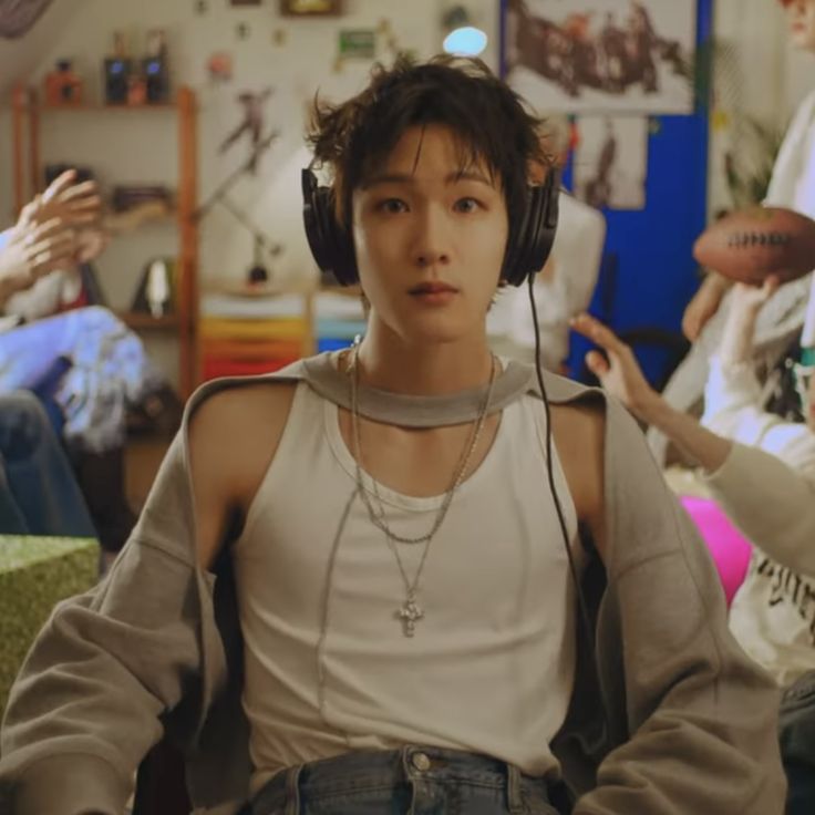 a young man wearing headphones sitting in front of a group of people with basketball hoops