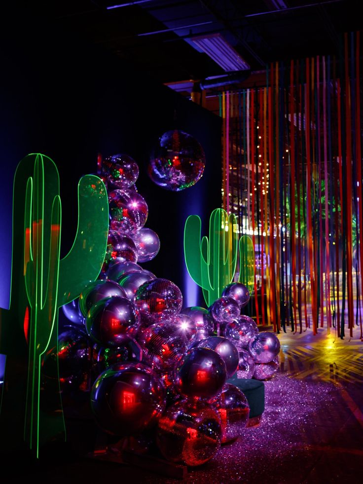 an artistic display with neon lights and cactus plants in the center, surrounded by disco balls