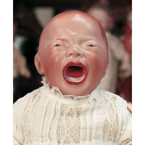 a baby doll with its mouth open and tongue out