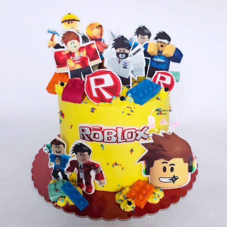 a yellow cake decorated with cartoon characters on it's sides and the words roblox spelled in red