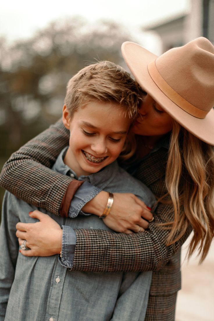 a woman hugging a young boy wearing a hat