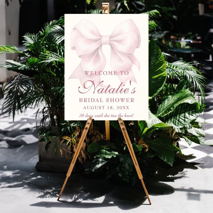 a welcome sign with a pink bow on it in front of some potted plants