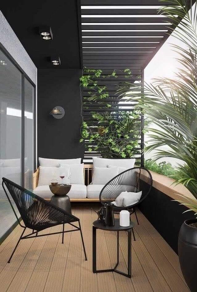 two black and white chairs sitting on top of a wooden floor next to a potted plant