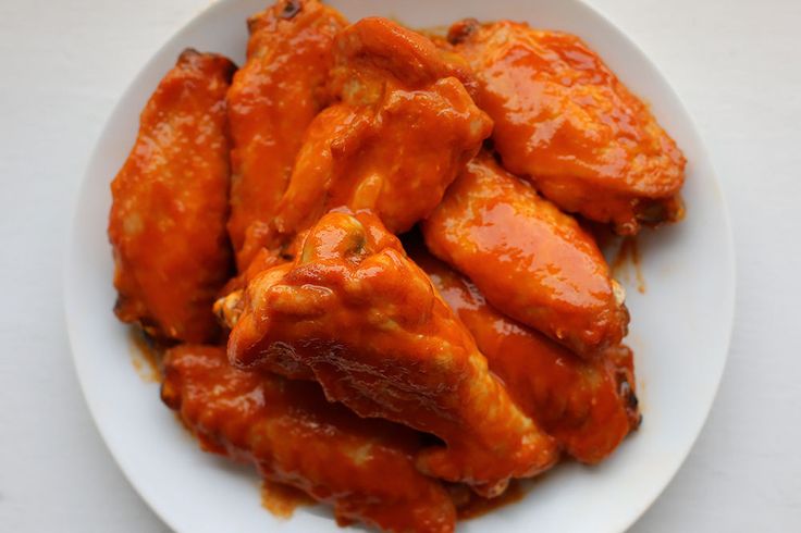 a white plate topped with chicken wings covered in sauce