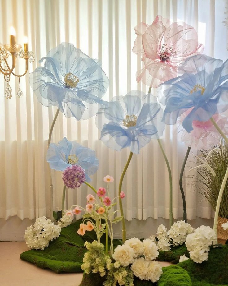 there are many flowers in the vases on the table and one is pink, blue, and white