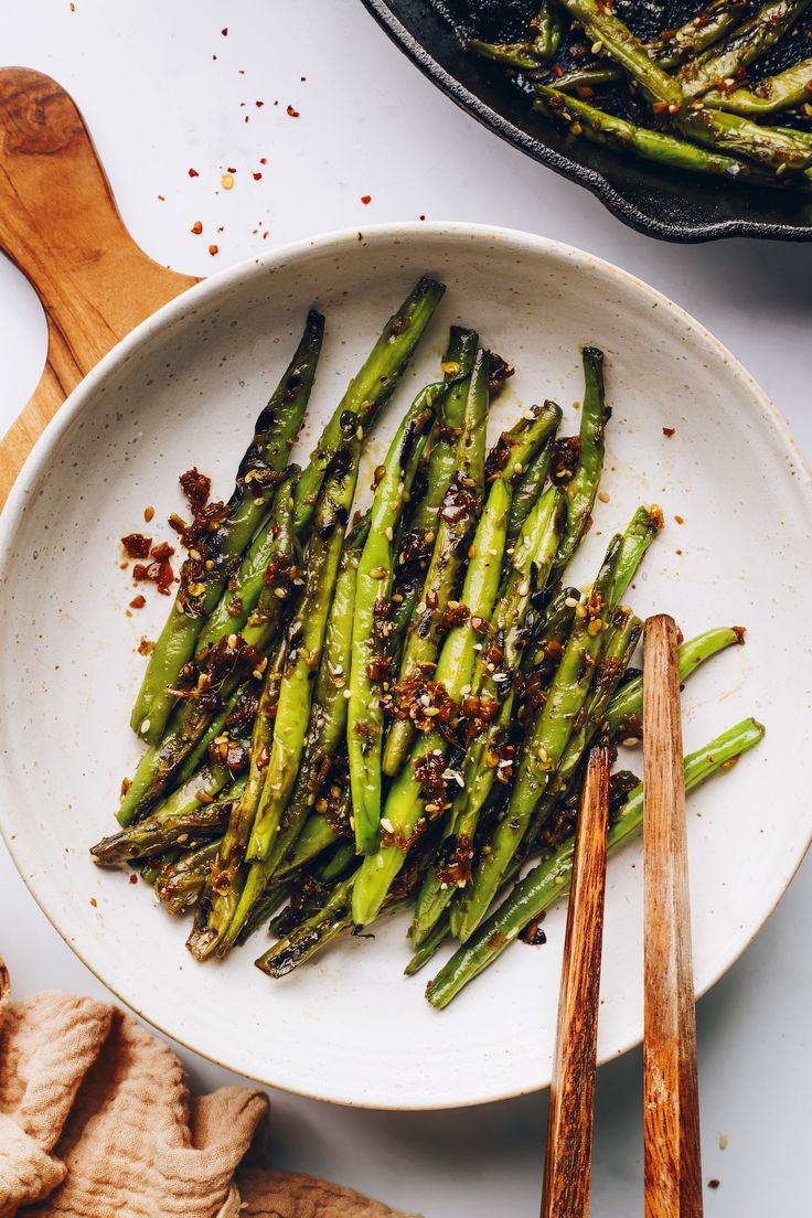 asparagus on a white plate with wooden spoons next to it and other ingredients