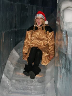 a woman sitting on top of a set of stairs wearing a santa hat and gold jacket