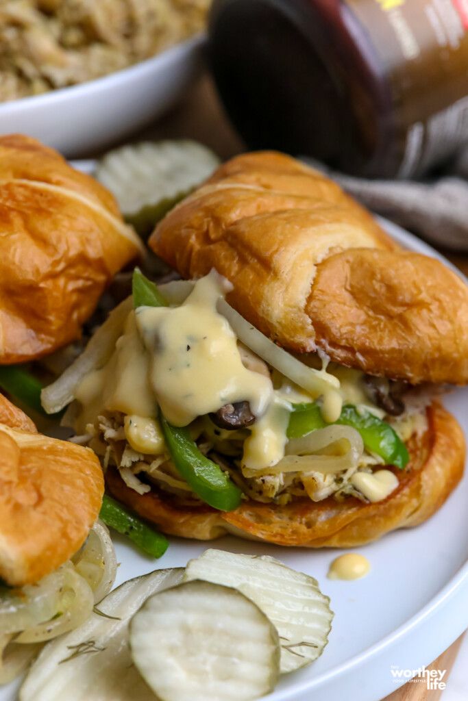 two sandwiches on croissant buns with green peppers, onions and mayonnaise