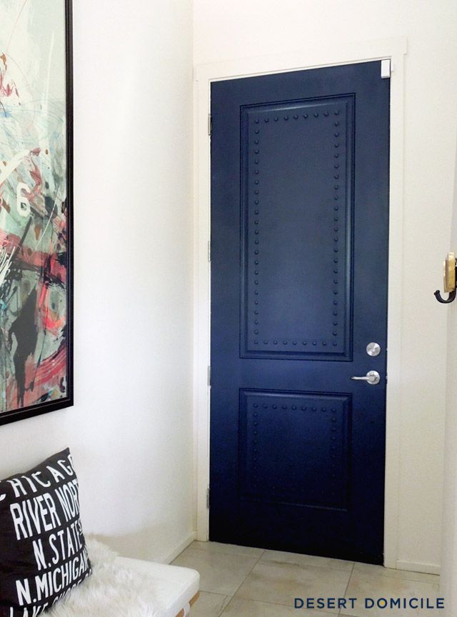 a blue door in a white room with a black and white pillow on the floor