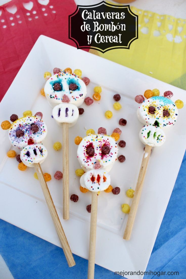 three sugar skulls on sticks decorated with candies and candy are sitting on a white plate