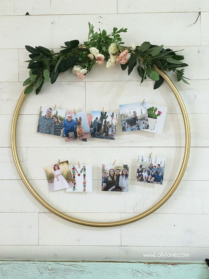 a circular gold frame with photos and greenery on it, hanging from the wall