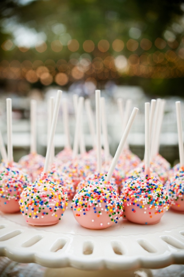 cake pops with sprinkles and white sticks on a plate at a wedding