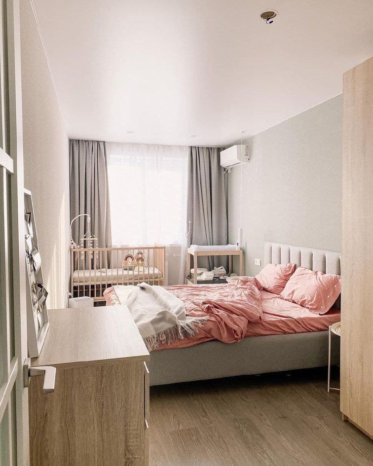 a bed room with a neatly made bed next to a wooden dresser and crib