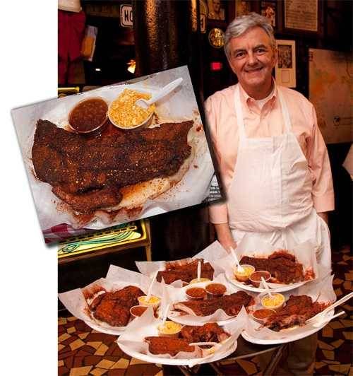 a man standing in front of a table full of food and plates with meat on them