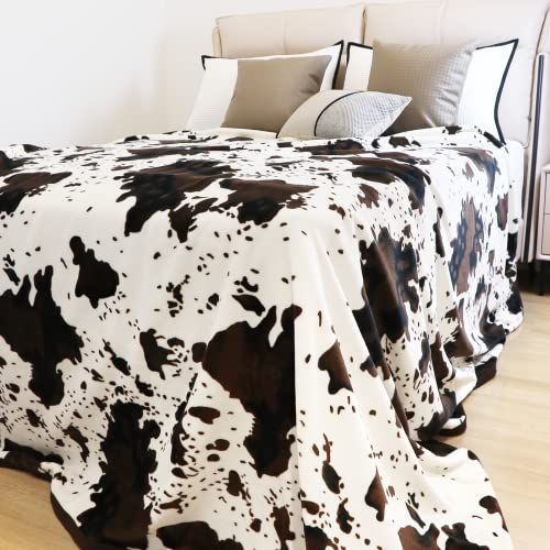 a black and white cow print blanket on a bed