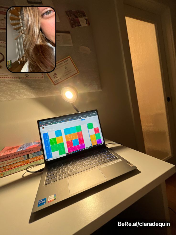 an open laptop computer sitting on top of a white desk next to a mirror with a woman's face