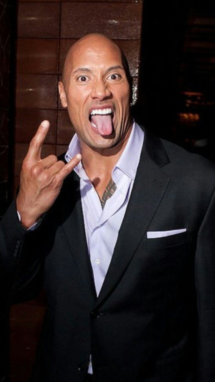 a man in a suit making a silly face with his fingers and mouth open while standing next to a wall