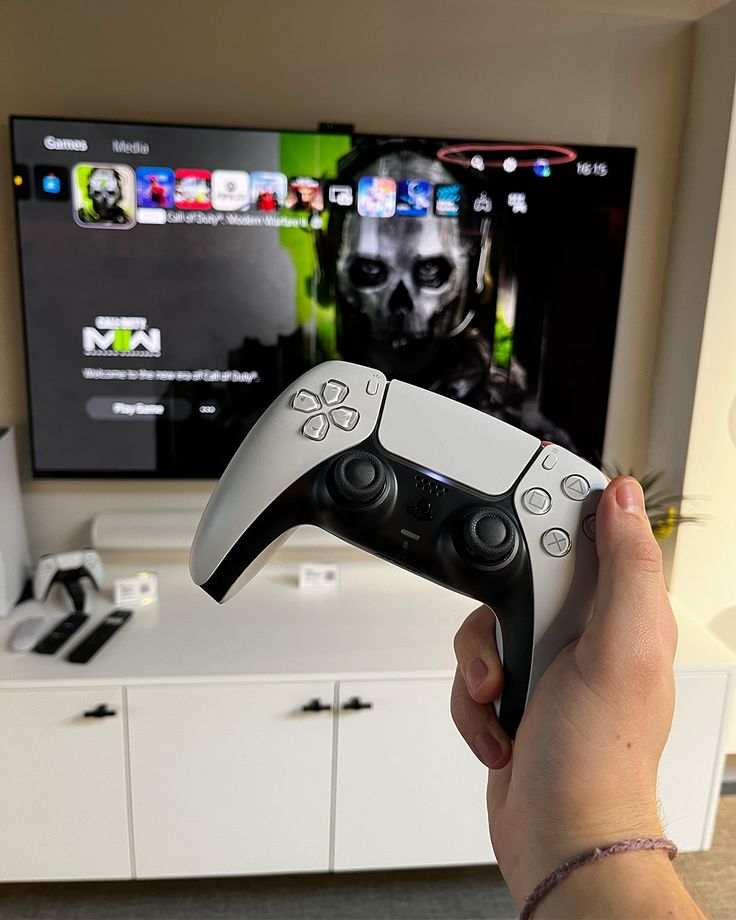 a person holding a video game controller in front of a flat screen tv on a white entertainment center