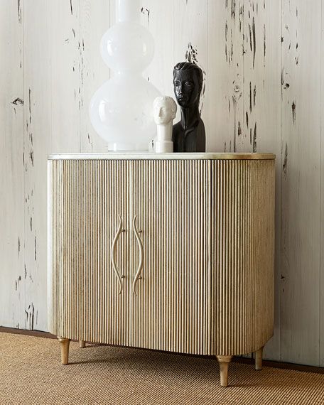 a white vase sitting on top of a wooden cabinet next to a black statue and lamp