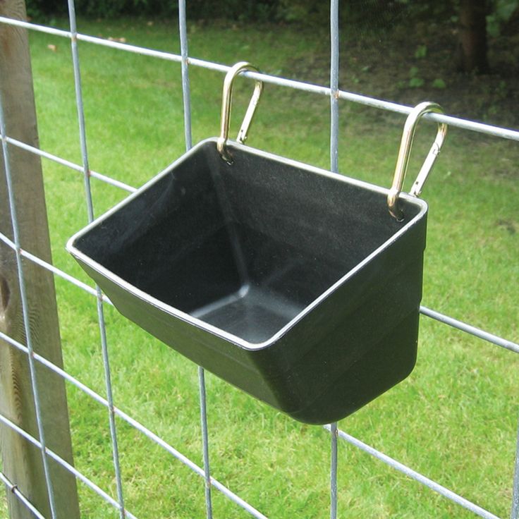 a black square bowl hanging on a wire fence