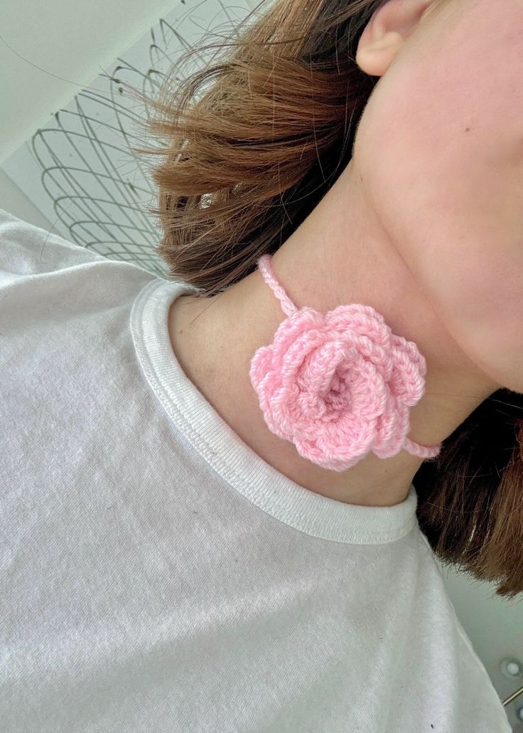 a woman wearing a pink crochet necklace with a flower on the front and side