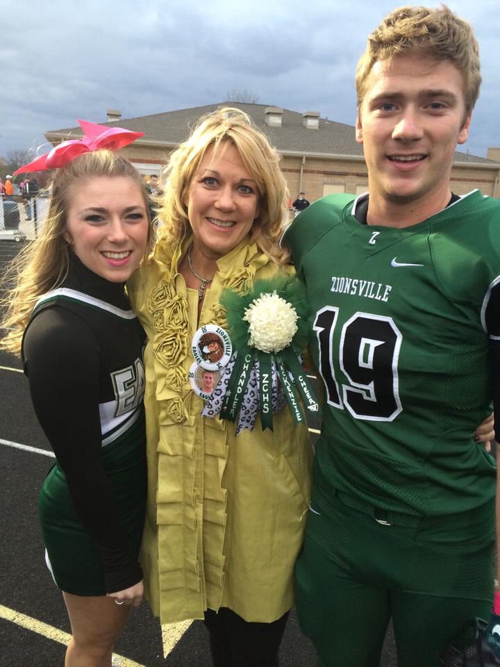 two women and a man standing next to each other in front of a football field