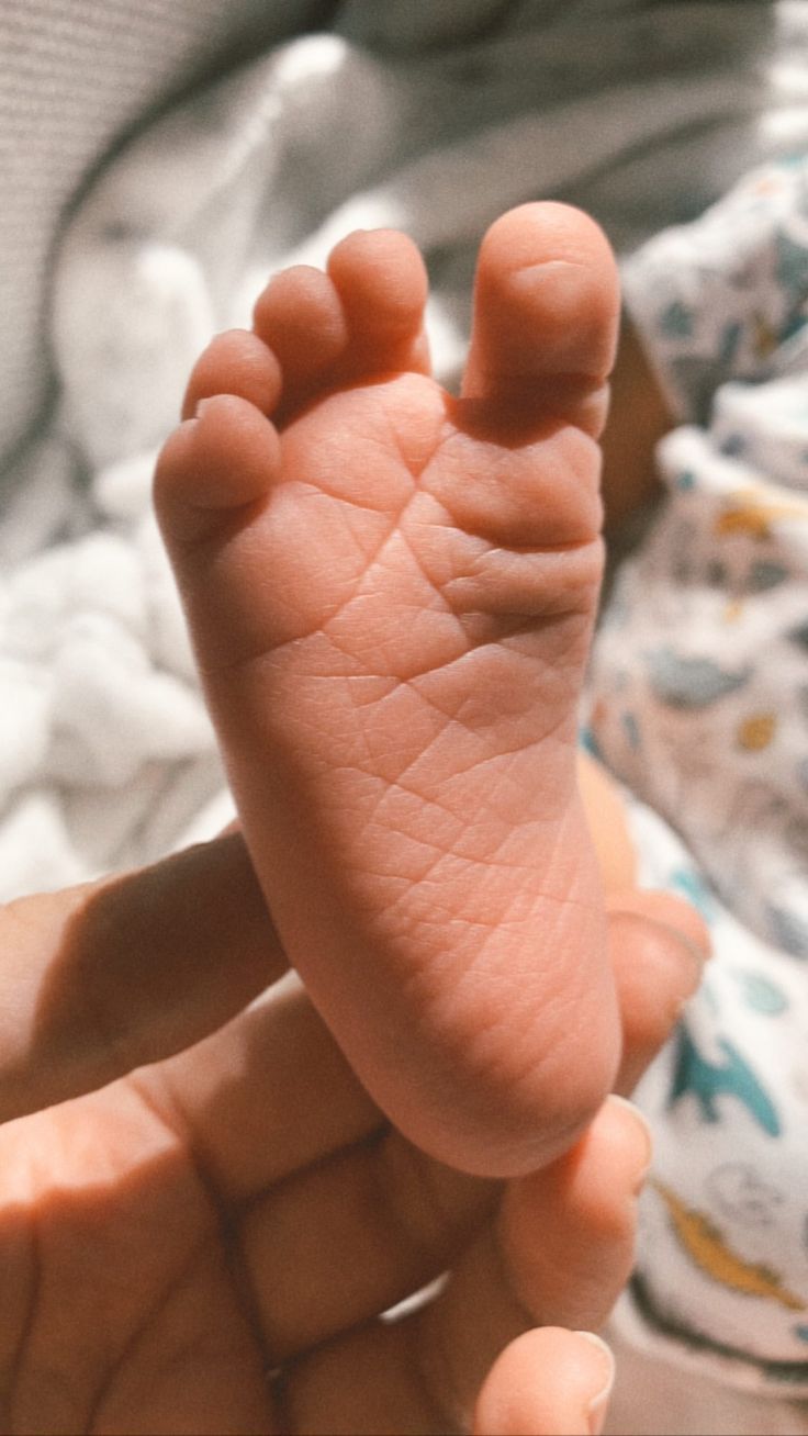 a baby's foot is being held in the palm of someones hand,