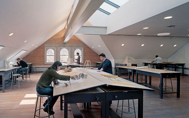 people are sitting at tables in an open room with skylights on the ceiling and windows above them