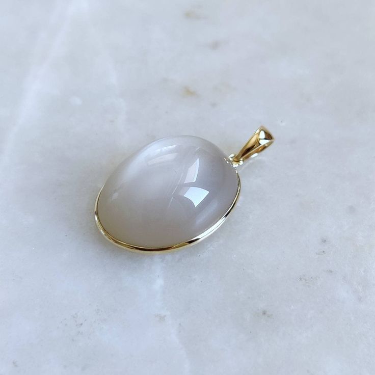 This stunning Pendant is set in 14k Solid Yellow Gold with Natural White Moonstone with utmost precision. It is a unique gemstone Pendant for nearly every occasion and is completely hassle-free jewelry. ITEM DETAILS: * GEM: White Moonstone  * GEM Size: 15x20mm * GEM Shape: Oval  * Gem Weight: 20.18 carats * Gold Purity: 14KT * Gold Weight: 0.62 gram * Total Weight of the Pendant: 4.66 gram The Gold purity is guaranteed and it comes with authentic 14KT gold hallmark. Since my items are handmade, they are absolutely nickel and lead free. CUSTOMIZATION: * Gemstone customization is available and it can be substituted with a gem of your choice. Kindly message me for the same. PACKAGING * The Pendant comes with layers of safe and secure wrapping along with Free handmade jewelry box with every pu White Moonstone Cabochon Jewelry, White Cabochon Moonstone Jewelry, Elegant Gold Moonstone Ring With Natural Stones, White Moonstone Oval Pendant Jewelry, White Moonstone Round Jewelry, White Moonstone Oval Pendant, White Moonstone Oval Cabochon Ring In 14k Gold, 14k Gold White Moonstone Oval Cabochon Ring, White Oval Cabochon Moonstone Ring In 14k Gold