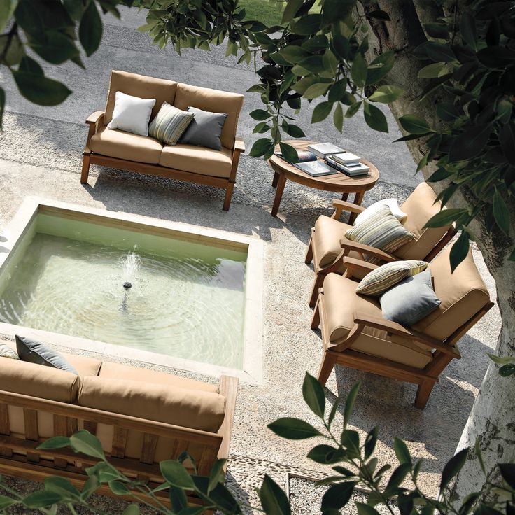 an outdoor living area with couches, chairs and a small pool in the middle