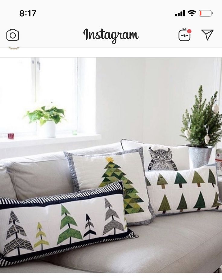 a couch with christmas trees on it in front of a window and potted plant