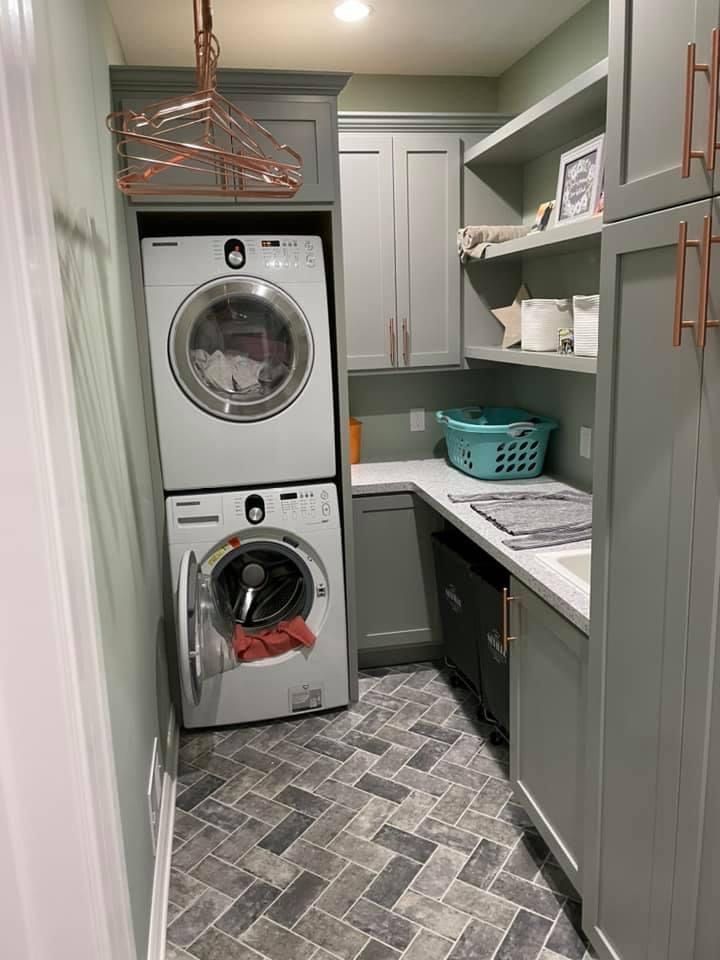 a washer and dryer in a small room with grey cabinets on the walls