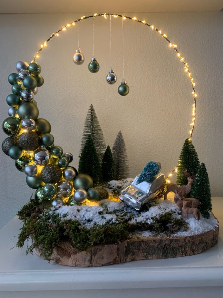 a christmas display with lights and ornaments on top of a table in front of a white wall