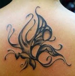 the back of a woman's neck with an artistic tattoo design on it