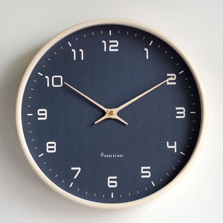 an analog clock on the wall with numerals and numbers in white, blue and beige