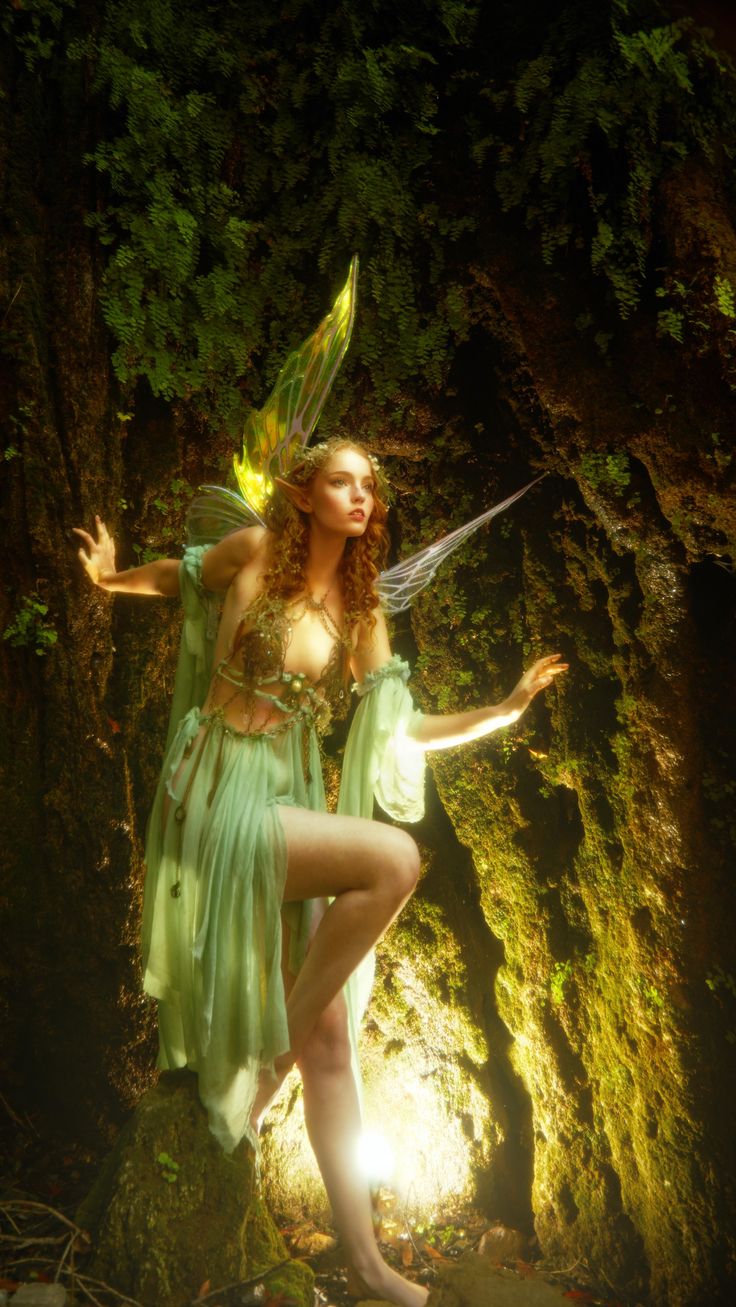 a woman dressed as a fairy standing in the woods