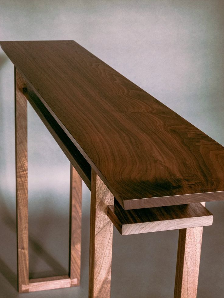 a long wooden table sitting on top of a hard wood floor next to a white wall