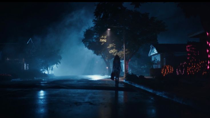 a person standing in the middle of a street at night with lights shining on them