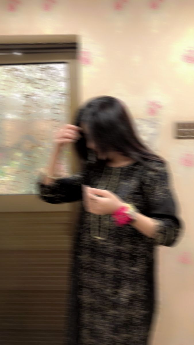 a woman standing in front of a window looking at her cell phone