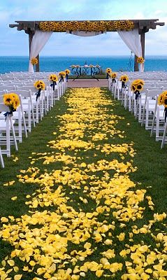 the aisle is decorated with yellow flowers and white chairs