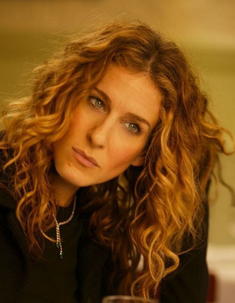 a woman sitting at a table with a wine glass in her hand and looking off to the side