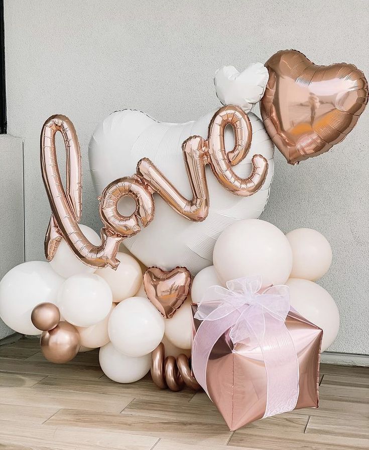 the balloon love sign is surrounded by white and rose gold balloons