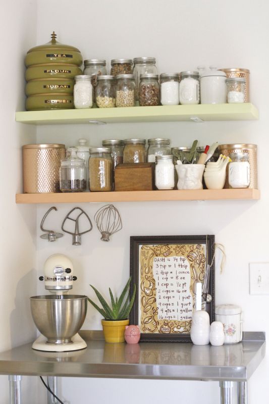 the shelves are filled with jars and other kitchen items, including a mixer on a table