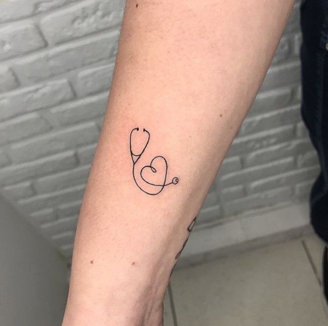 a woman's arm with a tattoo on it that has a stethoscope in the shape of a heart