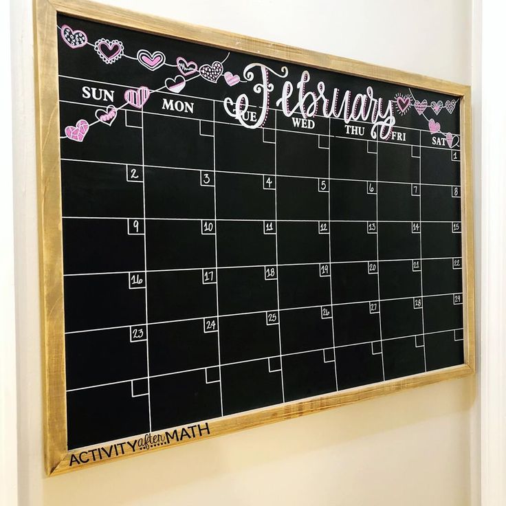 a chalkboard with the calendar written on it and hearts drawn on it, hanging in front of a wall