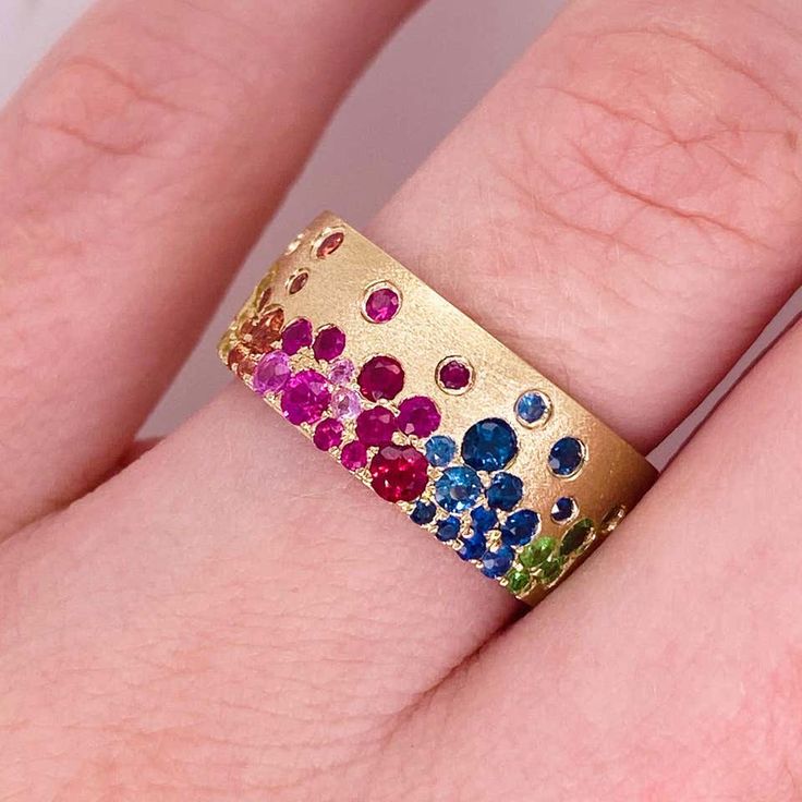 This lovely rainbow confetti is dripping with 1.36 carats of sapphires, rubies, and tsavorites and makes a bold statement as a cigar band. All the genuine gemstones are like a galaxy of flush set and the gold is textured. This band ring is breathtakingly colorful! Accented by lovely 14 karat brushed yellow gold with 1.36 carats total weight of genuine gemstones, this ring is amazing by itself and in a stack! The details for this beautiful ring are listed below:Metal Quality: 14K Gold (Available Confetti Ring, Galaxy Rainbow, Gold Jewellery India, Rainbow Confetti, Bezel Set Engagement Ring, Rainbow Jewelry, Gold Rings Fashion, Unique Wedding Bands, Star Jewelry