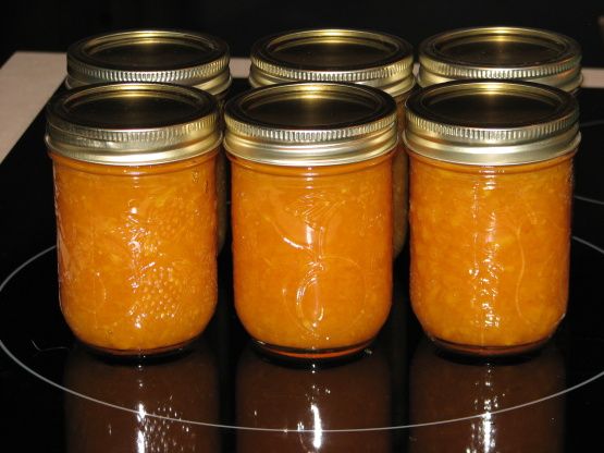 four jars filled with orange colored liquid sitting on top of a black countertop next to each other