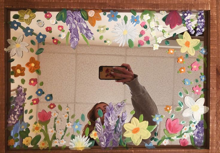 a woman taking a selfie in front of a mirror with paper flowers on it