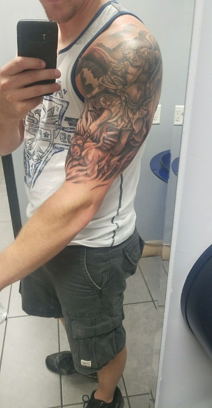 a man taking a selfie in the mirror with his cell phone and tattoos on his arm