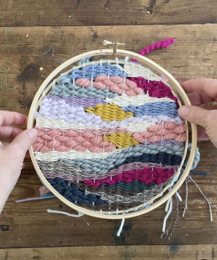 two hands are working on a colorful weaving project